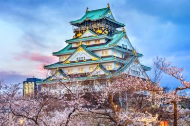 El castillo de Osaka rodeado de cerezos en flor al anochecer