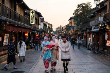 Calle tradicional del barrio de Gion en Kioto con mujeres en kimono al atardecer