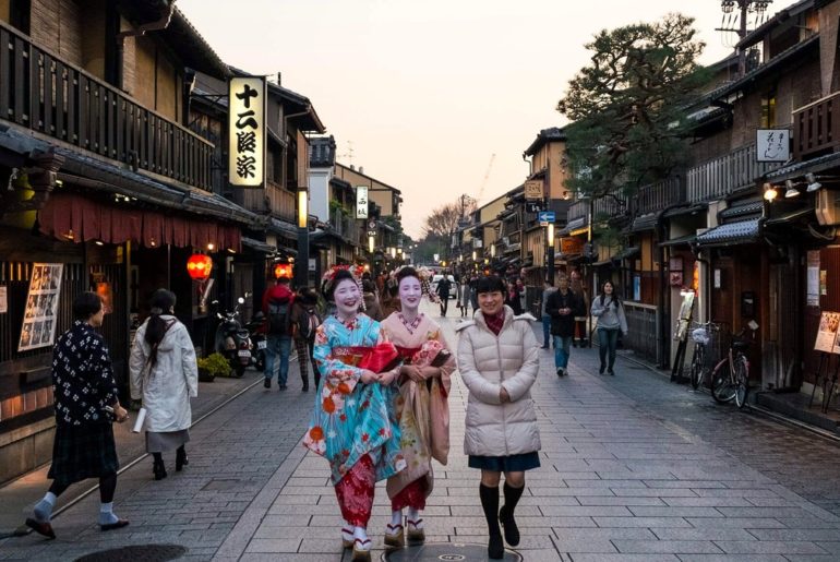 Calle tradicional del barrio de Gion en Kioto con mujeres en kimono al atardecer