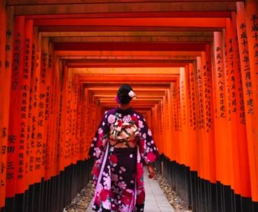 Túnel de puertas torii rojas en Fushimi Inari, Kioto, con una visitante en kimono